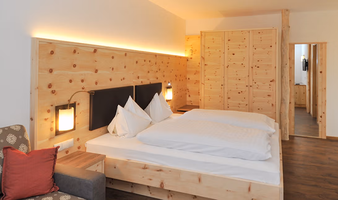 Gemütliches Doppelzimmer des Brunnerhof mit Naturholzmöbeln aus Fichte und gepolstertem Kopfteil.