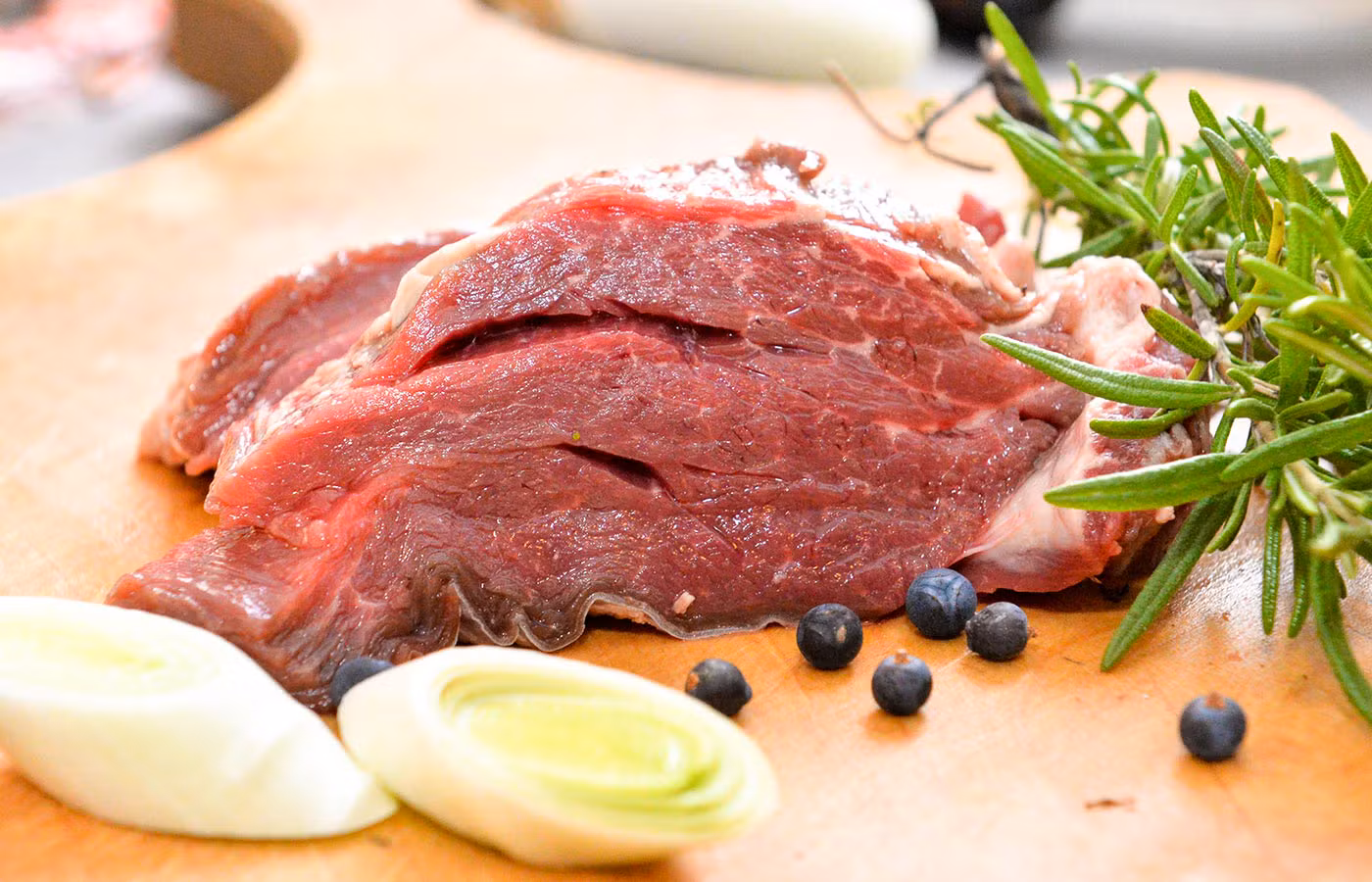 Ein St4ck rohes Fleisch mit Lauchstücken, Rosmarie und Wacholderbeeren