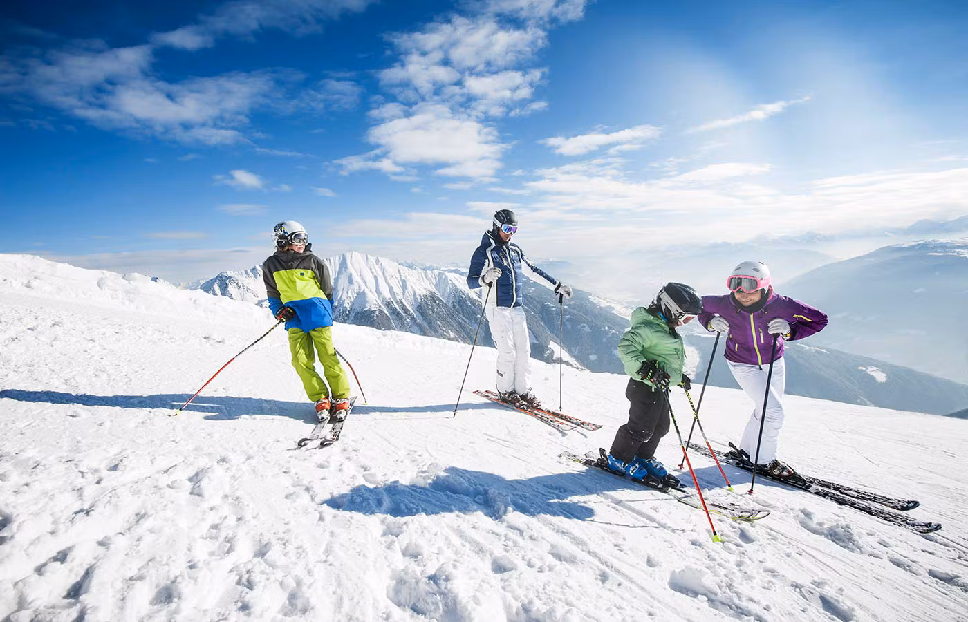 Famiglia felice scia sulle piste innevate dell'area Gitschberg Jochtal, Alto Adige, sotto un cielo azzurro.